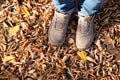 Male legs in gray classic leather shoes and blue jeans on brown yellow leaves on sunny autumn day. Lifestyle, top view Royalty Free Stock Photo