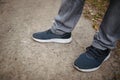 Male legs in jeans and sneakers walking out into the distance on the ground covered with fallen yellow leaves. Autumn arrival Royalty Free Stock Photo