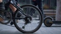 Male legs riding bicycle in black shoes at downtown close up. Rear wheel view. Royalty Free Stock Photo