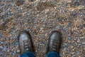 Male legs and shoes top view. Selfie feet in black tracking shoes or boots on a pebble beach.