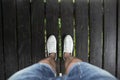 Male legs in shorts and white shoes on a wooden bridge,top view