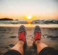 Male legs in sneakers on the seashore at sunset or sunrise
