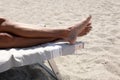 Male` legs rest on a sun bed on the beach