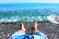Male legs while sunbathing, lying carefree in the water on pebbles near the coastline Royalty Free Stock Photo