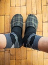 Male legs wearing old worm socks and slippers standing on old parquetry