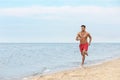 Handsome male lifeguard running on sandy beach