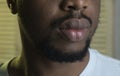 Male lips close up, jalousie background. African peoples beauty concept. Lips of Black macho with beard. Sensual big