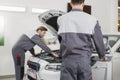 Male maintenance engineers examining car in workshop