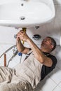 Specialist male plumber repairs faucet in bathroom