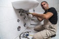 Specialist male plumber repairs faucet in bathroom