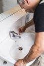 Specialist male plumber repairs faucet in bathroom