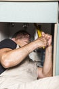 Specialist male plumber repairs faucet in kitchen