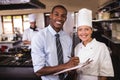 Male manager and female chef writing on clipboard in kitchen Royalty Free Stock Photo