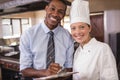 Male manager and female chef writing on clipboard in kitchen Royalty Free Stock Photo