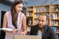 Male manager and female secretary consult work. Female employee pointing finger laptop presenting information with paper document Royalty Free Stock Photo