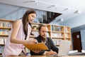 Male manager and female secretary consult work. Female employee pointing finger laptop presenting information with paper document Royalty Free Stock Photo