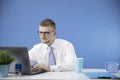 Male manager in office concentrates on laptop, accent on blue colour