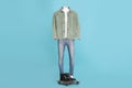 Male mannequin with boots dressed in white t-shirt, jeans and stylish jacket on light blue background Royalty Free Stock Photo