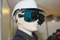 A male mannequin wearing protective cloths: welding goggles and white construction safety helmet, hard hat