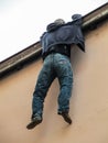 Male mannnequin hanging from the edge of a building