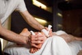 Male masseur doing a foot massage with aromatic herbal bags for his female patient in spa salon. Royalty Free Stock Photo