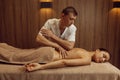 Male masseur rubbing hands to slim woman