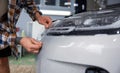 Male master in car service applying protective armor film to car body