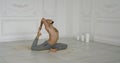 Male master of yoga is performing asana on floor indoors