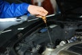 Male mechanic checking engine oil level in car service center Royalty Free Stock Photo