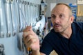 male mechanic choosing spanner from rack on wall