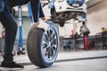 Male mechanic hold and rolling tire at repairing service garage background. Technician man replacing winter and summer tyre for