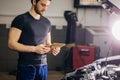 Mechanic using digital tablet next to an open hood in garage