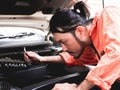 Male mechanic wearing orange color jumpsuit working on car engine outdoor,holding wrench and looking at engine