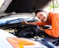 Male mechanic wearing orange color jumpsuit working on car engine outdoor , smiling to camera