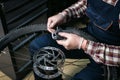 Male mechanic working in bicycle repair shop, mechanic repairing bike using special tool, wearing protective gloves. Young