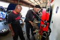 Male mechanics perform maintenance on a car in an industrial auto repair shop