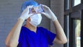 Male medical worker puts on protective gears like gloves, surgical face mask, bouffant cap, goggles