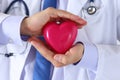 Male medicine doctor hands holding and covering red toy heart