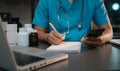 male medicine doctor, physician or practitioner in lab room writing on blank notebook and work on laptop computer with medical Royalty Free Stock Photo