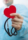 Male medicine doctor wearing hold in hands red toy heart and stethoscope closeup black background. Cardio therapeutist, physician Royalty Free Stock Photo