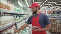 Handsome male merchandiser checking milk products with digital tablet