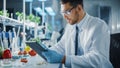 Male Microbiologist Working on Digital Tablet Computer and Creating Lab-Grown Vegetables. Microbio Royalty Free Stock Photo