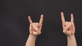 Male model is doing rock or  Devil`s horns hand sign with two hands on blackground Royalty Free Stock Photo