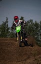 Male motorbike rider ascending a dirt hill, wearing full safety gear, including a helmet and boots