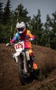 Male motorbike rider ascending a dirt hill, wearing full safety gear, including a helmet and boots