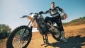 Male motorcycler is holding his leg on a pedal of his autobike and looking round