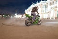 Male motorcyclist drifted night on your his sport green motorcycle on the square in the centre of the old town