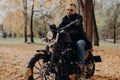 Male motorcyclist drives in nature on fast bike, wears shades, black jacket, gloves, jeans and boots, enjoys autumn season, spends