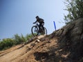 Male mountain biker wearing protective gear and a helmet is speeding down a steep downhill course
