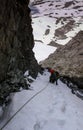 Male mountain climber in a very steep and narrow gully on a rope and looking down Royalty Free Stock Photo